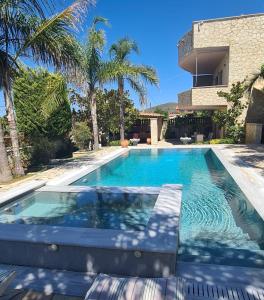 a swimming pool in front of a house with palm trees at Entire Villa with private pool in Skála