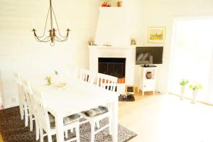 a white dining room with a white table and a fireplace at Stuga med sjöutsikt. in Ingatorp