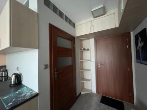 a small kitchen with a wooden door and a staircase at BARBIE & KEN - Apartamenty na ostatnim piętrze w Dominikana Resort & SPA Sianożęty in Sianozety
