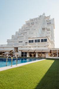 - un grand bâtiment avec une piscine en face dans l'établissement Hotel Los Delfines, à La Manga del Mar Meno