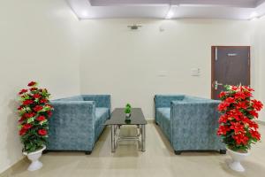 a waiting room with two blue chairs and red flowers at FabHotel Pink Palace in Jaipur
