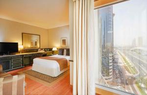a hotel room with a bed and a large window at Millennium Plaza Downtown, Dubai in Dubai