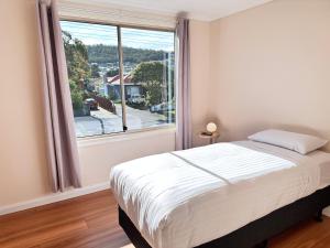a bedroom with a bed and a large window at Beach House Bellerive Hobart Eastern Shore in Bellerive