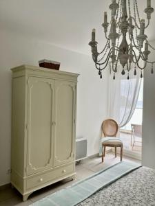 Zimmer mit einem Schrank, einem Stuhl und einem Kronleuchter in der Unterkunft Le Bleu Mer in Sète
