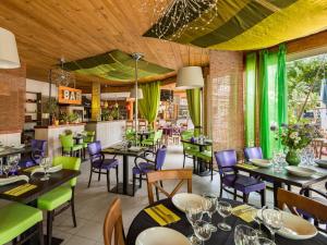un restaurant avec des tables, des chaises et des rideaux verts dans l'établissement Lagrange Vacances Les Mazets de Gaujac, à Gaujac