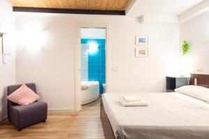 1 dormitorio con cama, silla y bañera en Rega Holiday House, en Nápoles