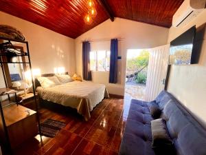 a bedroom with a bed and a couch at Chalé Verde morro da baleia. in Alto Paraíso de Goiás