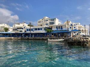 a boat in the water in front of a group of buildings at Walk on the beach in seconds - Studio with Apollon beach view balcony in Apollon