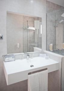 y baño con lavabo blanco y espejo. en Hotel Los Delfines en La Manga del Mar Menor