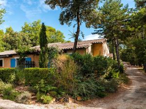 une maison dans les bois avec des arbres et des buissons dans l'établissement Lagrange Vacances Les Mazets de Gaujac, à Gaujac