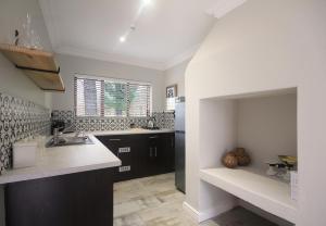 a kitchen with black cabinets and white counter tops at Stony Brook Cottages in Franschhoek