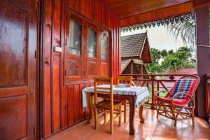 Habitación con balcón con mesa y sillas. en Zuela Guesthouse, en Luang Namtha