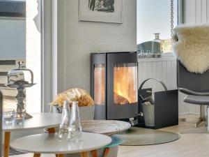 a fireplace in a living room with two tables at Apartment Tarvo - 500m from the sea in NW Jutland by Interhome in Pandrup