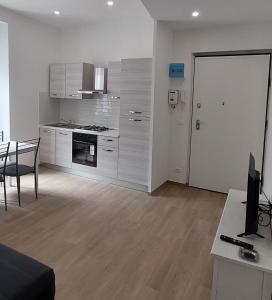 a kitchen with white cabinets and a table and a desk at FIUMARA MALL Apartment in Genoa