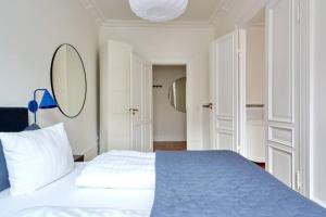 a bedroom with a bed with a blue blanket and a mirror at Spacious 3 Bedroom Manor Flat Next to Tivoli in Copenhagen