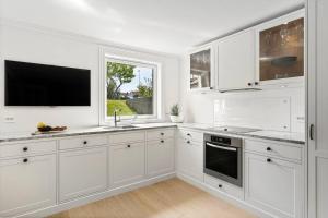 a white kitchen with white cabinets and a tv at Exclusive apartment by the ocean in Tananger