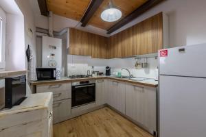 cocina con nevera blanca y armarios de madera en Relais Castel d'Emilio - Casa BLU, en Agugliano