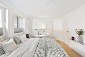 1 dormitorio blanco con 1 cama grande y lavamanos en Exclusive apartment by the ocean, en Tananger