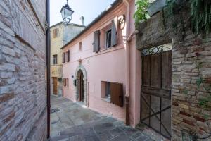 un callejón en un casco antiguo con edificios rosados en Relais Castel d'Emilio - Casa BLU, en Agugliano