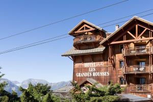 un gran edificio de madera con un cartel. en Grandes Rousses Hotel & Spa en L'Alpe-d'Huez