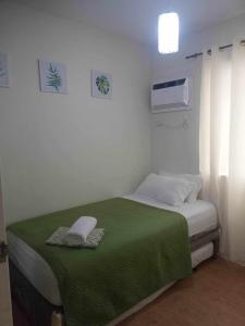 Dormitorio pequeño con cama con manta verde en 2BR Casa Mia Sanremo Oasis Cebu en Talisay