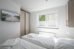 - une chambre blanche avec 2 lits et une fenêtre dans l'établissement Ostseecamp Lübecker Bucht Ferienhaus "Beachhouse" mit kostenlosen Saunazugang, à Scharbeutz