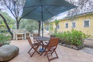 uma mesa e cadeiras com um guarda-sol num pátio em Villa Ventiseri - Maison vue montagne em Ventiseri