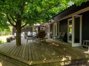 a wooden deck with a tree and chairs on it at Holiday Home Bistra - 280m from the sea in Sealand by Interhome in Vejby