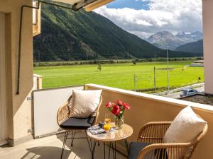a balcony with a table and chairs and a view of a field at Apartment Chesa Muntarütsch by Interhome in Samedan