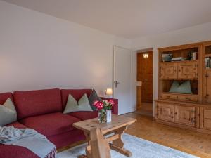 a living room with a red couch and a table at Apartment Chesa Muntarütsch by Interhome in Samedan