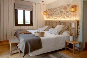 una camera da letto con un grande letto bianco e un muro di pietra di San Benito, finca privada cerca de Gredos con piscina a Mejorada