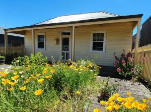 a small house with flowers in front of it at Darcy's Cottage on Piper in Kyneton