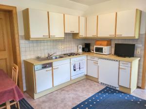 cocina con armarios blancos, fregadero y microondas en Apartment Sonnenschein by Interhome, en Spiss