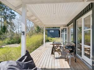 eine Holzveranda mit einem Tisch und einem Grill in der Unterkunft Holiday Home Nille - 485m to the inlet in Sealand by Interhome in Ølsted