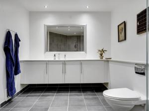 a white bathroom with a toilet and a sink at Apartment Bena - 150m from the sea in Sealand by Interhome in Dronningmølle