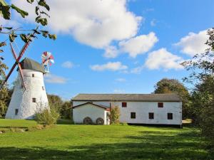 a white barn with a windmill on a field at Holiday Home Gudmand - 600m from the sea in Bornholm by Interhome in Vester Sømarken