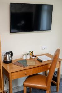 a desk with a laptop and a television on a wall at St Leonards Hotel by Greene King Inns in Saint Leonards
