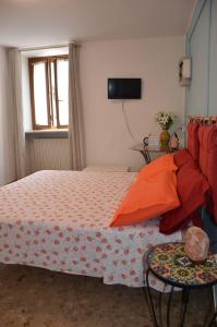 ein Schlafzimmer mit einem Bett mit orangefarbenen Kissen und einem Fenster in der Unterkunft Da Giulia in Belluno Veronese