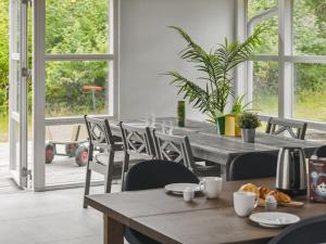uma sala de jantar com mesas, cadeiras e janelas em Holiday Home Haghbarth - 400m from the sea in Lolland- Falster and Mon by Interhome em Dannemare