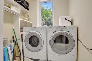 Duas máquinas de lavar roupa numa lavandaria com uma janela em Coastal Condo Deerfield Beach Retreat 3 bed 2 bath em Deerfield Beach