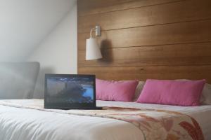 ein Laptop auf einem Bett mit rosa Kissen in der Unterkunft Hotel Lou Granva in Grande Riviere