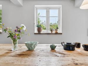 een tafel met een vaas met bloemen en een raam bij Apartment Erich - 200m from the sea in Bornholm by Interhome in Hasle