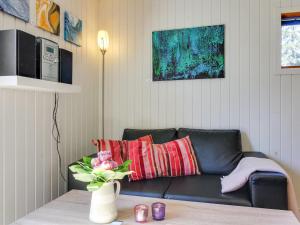 a living room with a black couch and a vase with flowers at Apartment Kolja - 3km from the sea in Western Jutland by Interhome in Blåvand