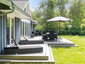 a patio with a table and an umbrella on a house at Holiday Home Josina - 675m from the sea in Sealand by Interhome in Tjørneholm
