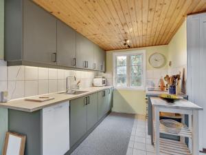 Una cocina con gabinetes grises y techo de madera. en Holiday Home Ljuba - 700m from the sea by Interhome, en Oksbøl