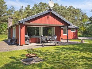 een rode hut met een grill in een tuin bij Holiday Home Keyla - 3-2km from the sea in Western Jutland by Interhome in Rømø Kirkeby