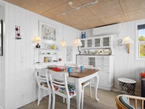 uma cozinha branca com uma mesa de madeira e cadeiras em Holiday Home Steen - 30m from the sea in Funen by Interhome em Vejstrup