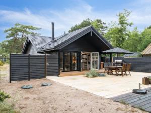 a black house with a patio and a table at Holiday Home Jensen - 175m from the sea in Sealand by Interhome in Tjørneholm