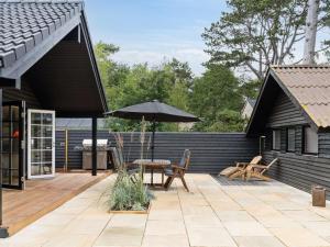 a patio with a table and an umbrella at Holiday Home Jensen - 175m from the sea in Sealand by Interhome in Tjørneholm