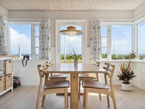 uma sala de jantar com mesa, cadeiras e janelas em Holiday Home Mirkka - 50m from the sea in Funen by Interhome em Asperup
